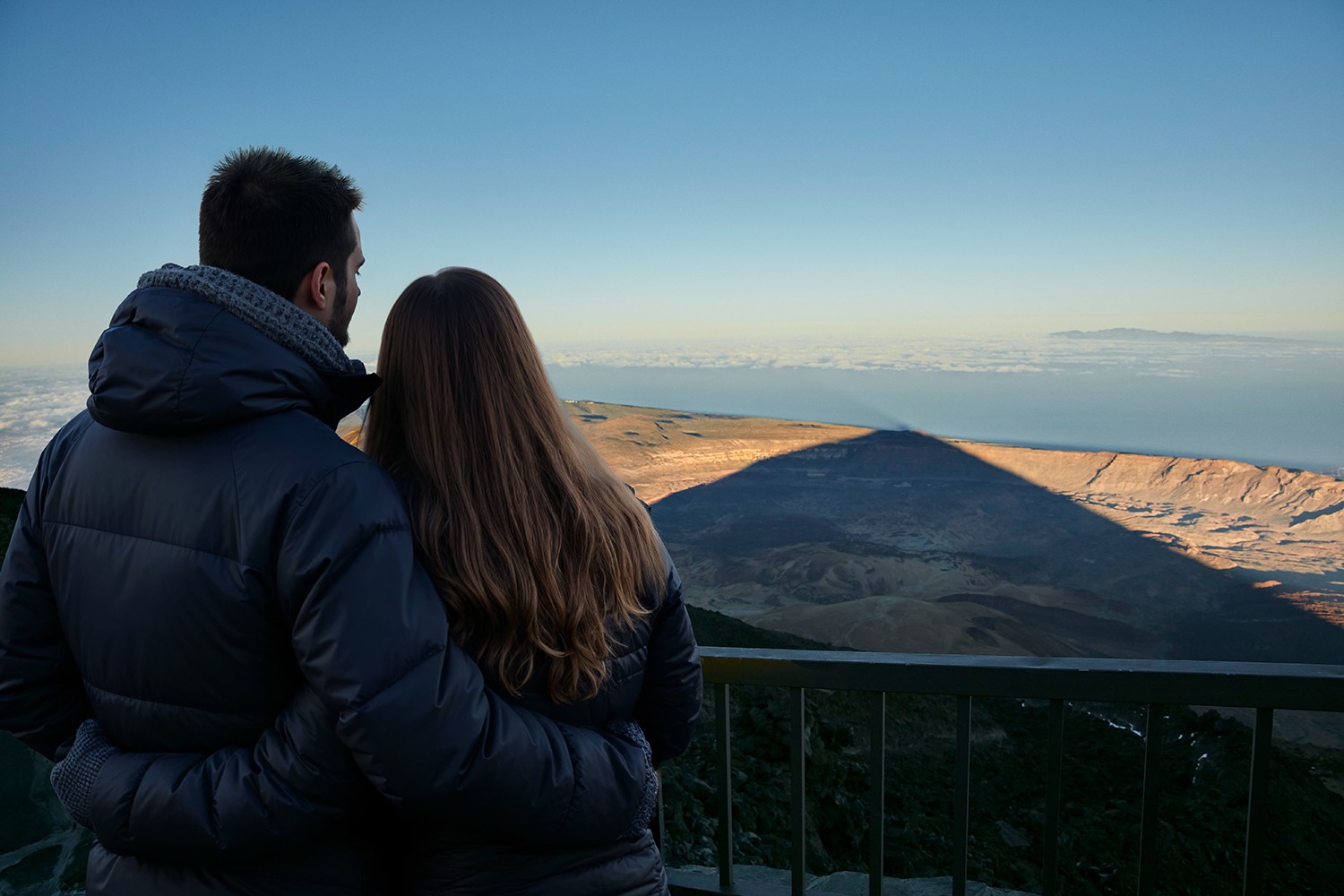 Stel kijkend naar het schouwspel van de schaduw van de Teide vanaf het terras met uitzicht op de kabelbaan