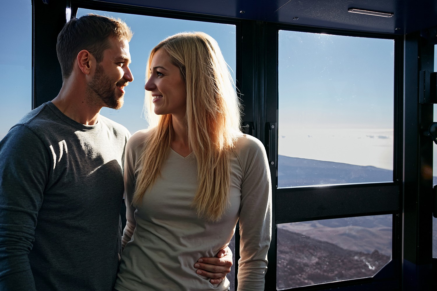 Couple regardant à travers la vitre du téléphérique qui monte, en groupe exclusif allant admirer le coucher de soleil